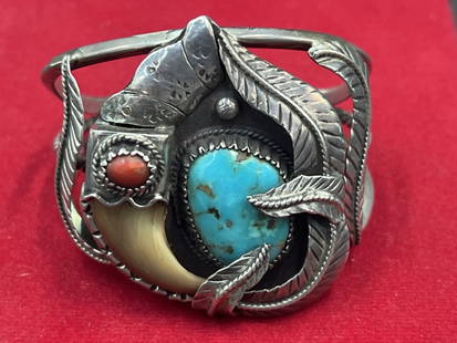 Large Navajo 'Kakiki' Signed Cuff Bracelet: Silver cuff bracelet, engraved signature Kakiki (Navajo, 20th c.), large ornament with feathers, turquoise, red coral, and claw, on a split shank cuff. Opening measures 1 1/4" and inside is 5.5". Top