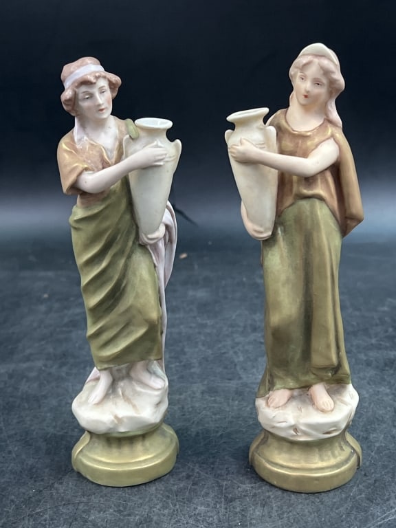 Antique Royal Dux Porcelain Figurines: Depicts female water carriers carrying amphora vases. Produced in Bohemia now known as Czech Republic. Figures feather polychrome accents in shades of taupe, pink and amber. Marked pink triangle with