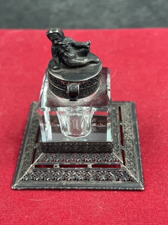 Vintage Inkwell: Sterling silver Include glass ink container. Base and lid gesture intricate metalwork. Figurine on top depicts a resting or lounging figure. Measures about 2.5"h. Condition consistent with