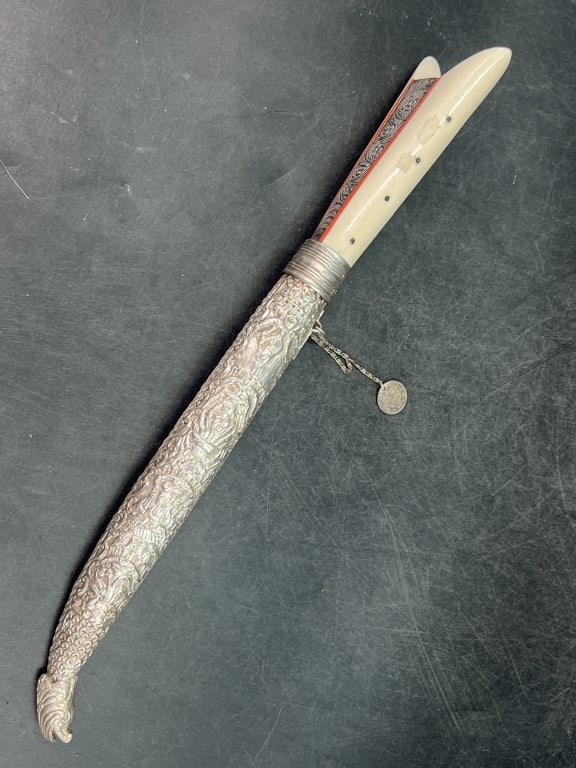 Cretan Knife with Silver Sheath: Straight steel blade partially engraved on the flat. Hand with bone plates with tang engraved with a stylized motif and flowers. Richly decorated silver scabbard. Greece 19th century. 