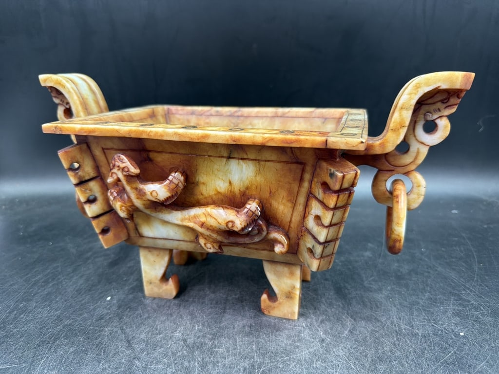 Vintage Chinese Carved Censer: Features intricate carvings of stylized creatures, such as dragons. Vessel typically has a rectangular body and yellow to brownish hue indicating the type of jade use. Measures 7" x 13" x 6". See