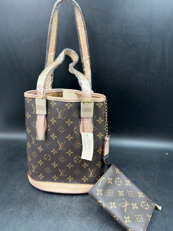 Louis Vuitton Petit Bucket Monogram Canvas Bag: Has original hang tag and plastic covering on handle. Also has feet on bottom and small pouch with chain. Designed with adjustable strap handles and brass hardware. Leather lining with a zipper