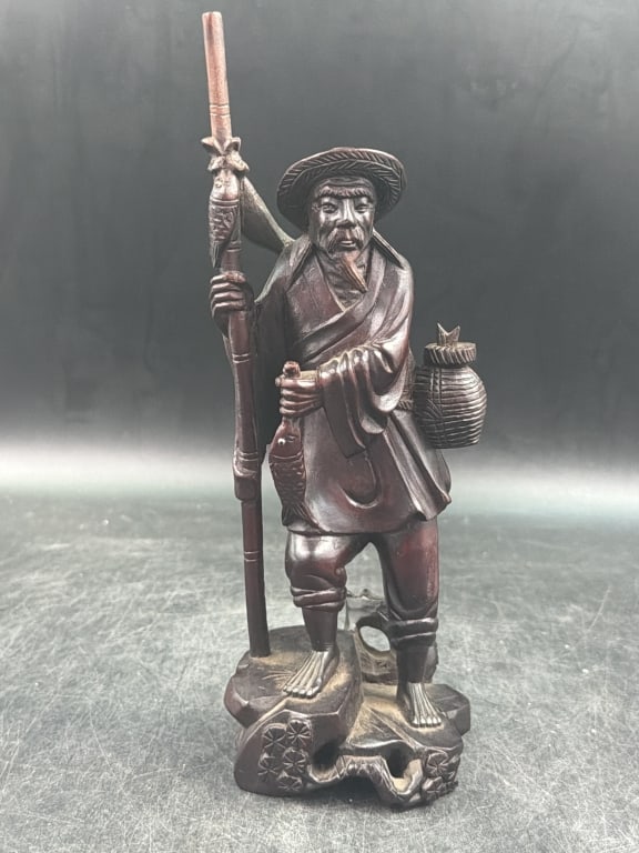 Chinese Boxwood Fisherman Statue: Intricate details and dark finish. Carved from boxwood featuring a dark brown finish. Fine handwork, including visible textures in the clothing, hands and feet. Measures10.5". Condition is consistent