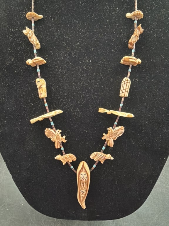 Native American Fetish Necklace: Hand carved light colored animal figures and stylized shapes. Central pendant is elongated carved figure with intricate facial details. Carved motifs on the necklace include a bear and eagle with
