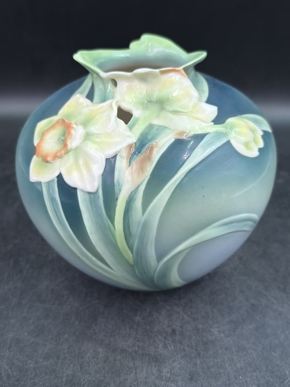 Franz Collection Daffodil Vase: Features a distinctive three dimensional sculpted floral relief. Art Nouveau inspired. Daffodil flowers with flowing green stems against a soft blue and white ombre background. Measures 6 3/8.