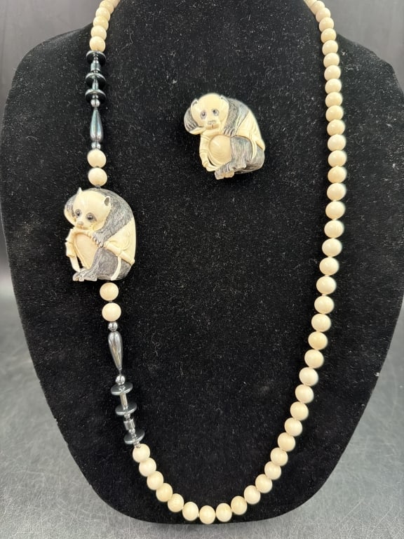 Vintage Japanese Panda Bear Necklace with Brooch: Necklace features cream colored uniform beads integrated with carved foal ornament depicting a seated panda. Dark contrast defines the eyes, ears and limbs. Accompanied by matching brooch. Condition