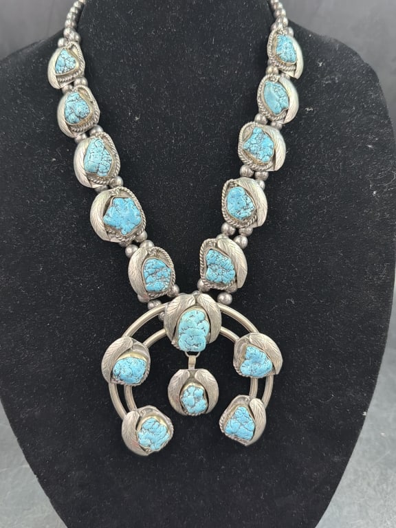 Native American Sterling Turquoise Squash Blossom: A traditional piece of Southwestern jewelry. Raw cut turquoise set in nickel silver complete with matching naja (3 1/4" x 3 3/4") pendant. Weighs a total of 250.2g and condition is good. See pictures.