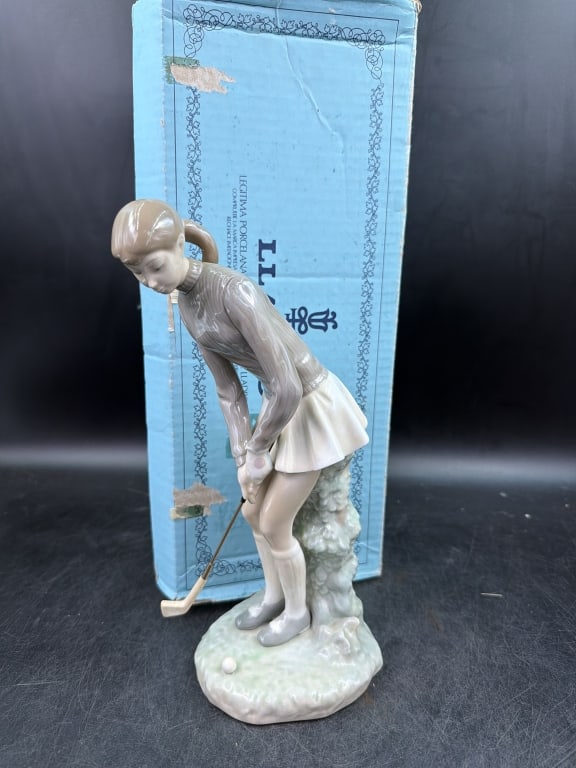 Lladro 'Lady Golfer': Comes with original box. Porcelain figurine of woman in grey top and white skirt preparing to swing with gold club. Measures 11 and condition is good, see pictures. No refunds given.