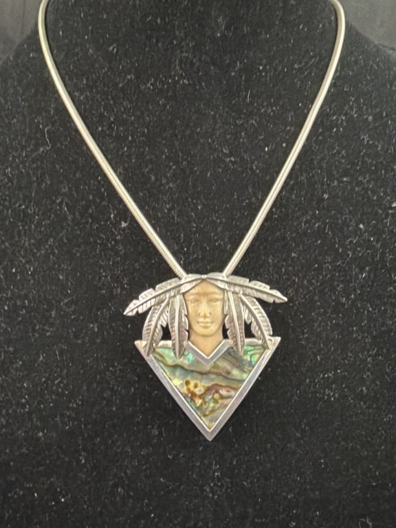 Native American Inlay Sterling Silver Pendant: with Necklace. Features a finely detailed face carved depicting a Native American face adorned with a silver feather headdress. Lower triangular portion is embellished with vibrant abalone shell inlay