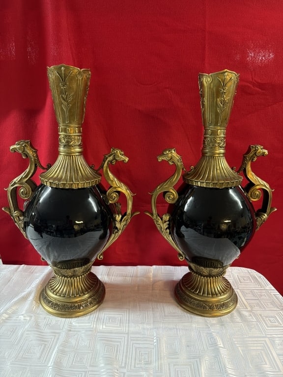 Ornamental Black Ceramic Vase Pair: Feature ornate brass handles shaped like mythical creatures. Vases accented with gilt bronze or brass mounts. neoclassical or French Sevres style urns. Measures 25" x 15". Condition appears good, see 