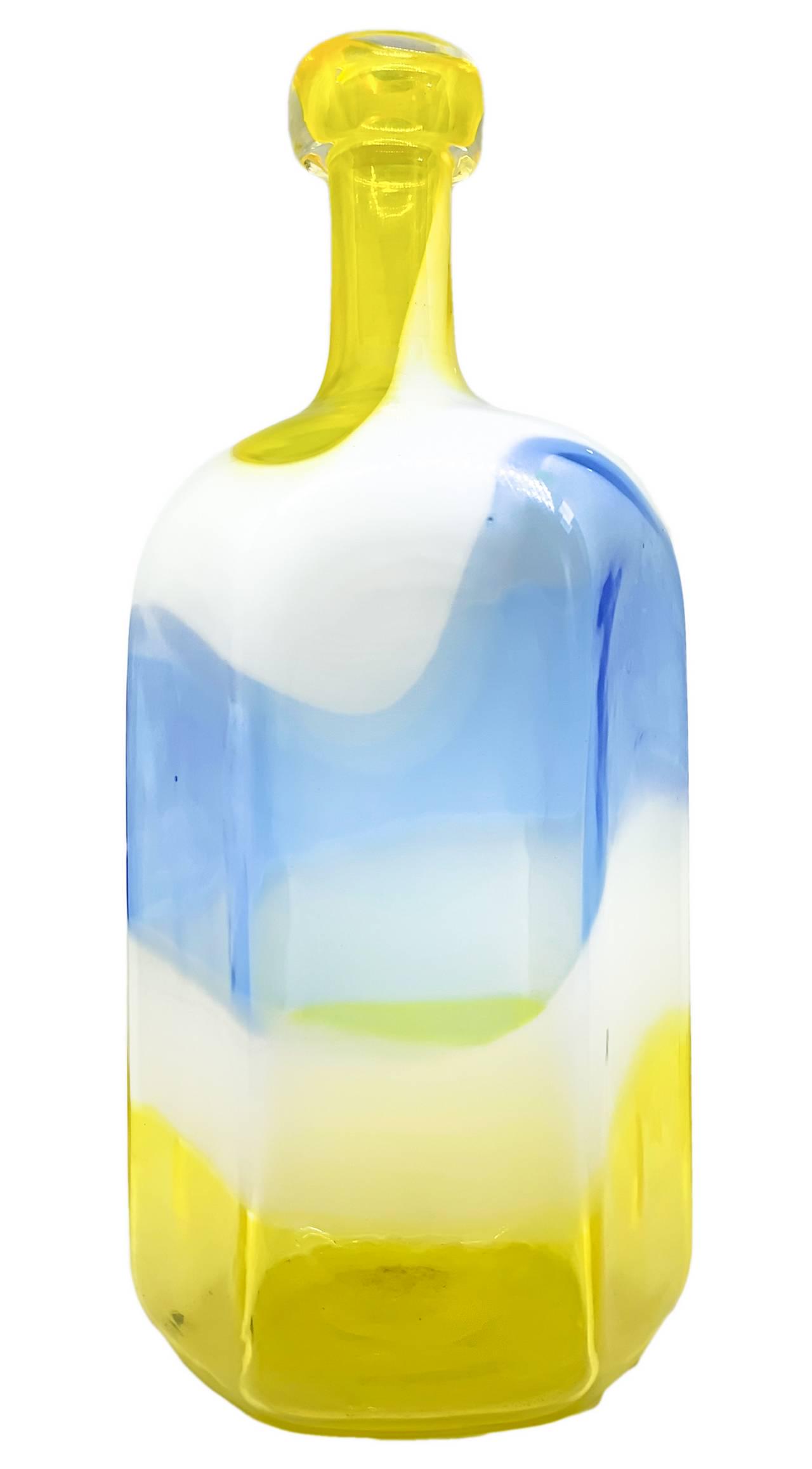 Bottle in Murano glass, hexagonal shape with a surface: Bottle in Murano glass, hexagonal shape with a surface area in polychrome bands in shades of yellow, white and blue. Applications in transparent glass paste at the top. H 33 cm