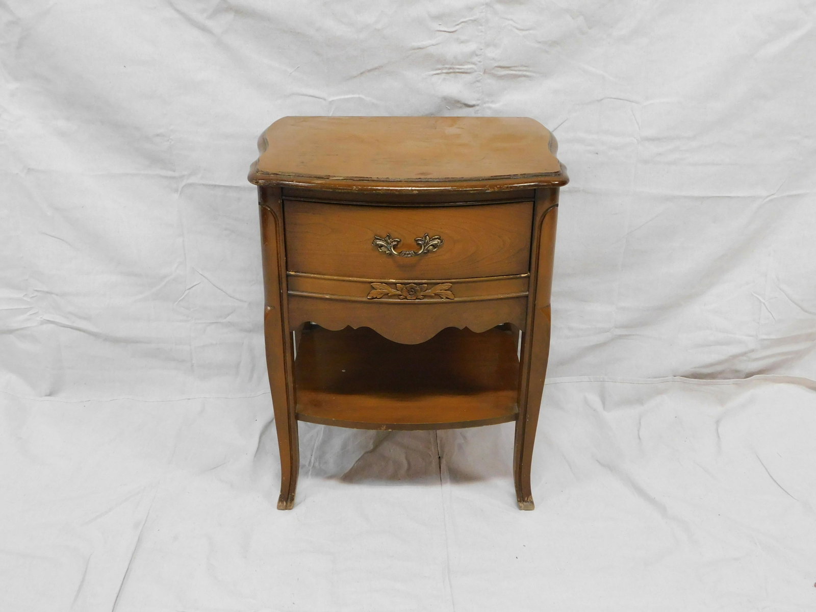 French Nightstand: French Nightstand by Bassett in good condition with some roughness to finish on top, dovetailed drawer, brass hardware, serpentine front, 26''H x 22''W x 16.5''D