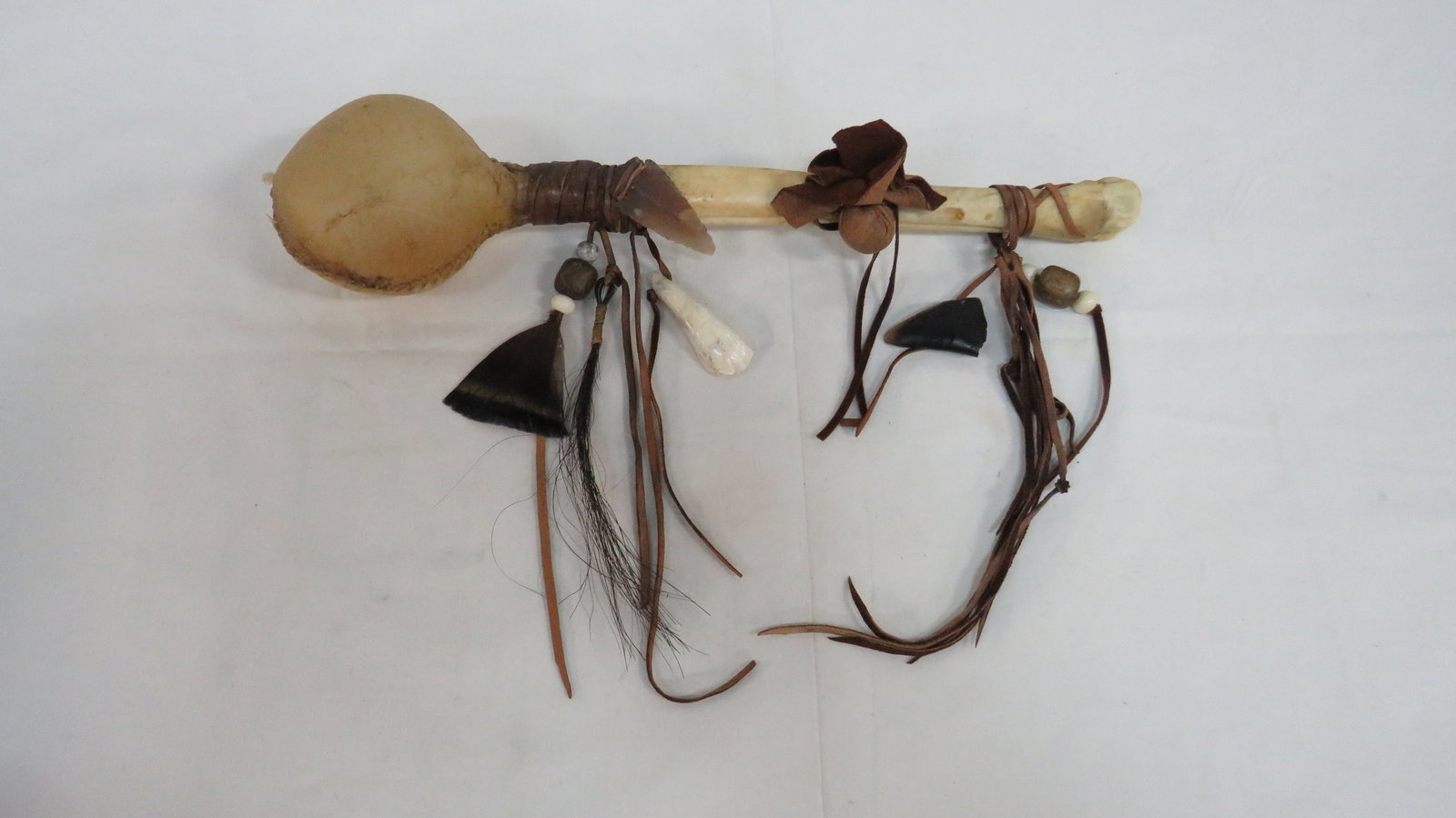 Native American Navajo Ceremonial Rattle: Native American Navajo Ceremonial Rattle in good condition. Rawhide head attached to deer leg bone with feathers, horsehair, arrowhead, medicine bag, and a bear claw. 14"L