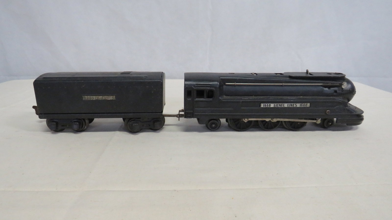 Lionel 1668 Train Torpedo Locomotive & Tender: Lionel 1668 Train Torpedo Locomotive & Tender. "O" gauge black torpedo style locomotive and tender. Good untested condition with are related wear. Locomotive measures 3"H x 9.5"L x 2.5"W