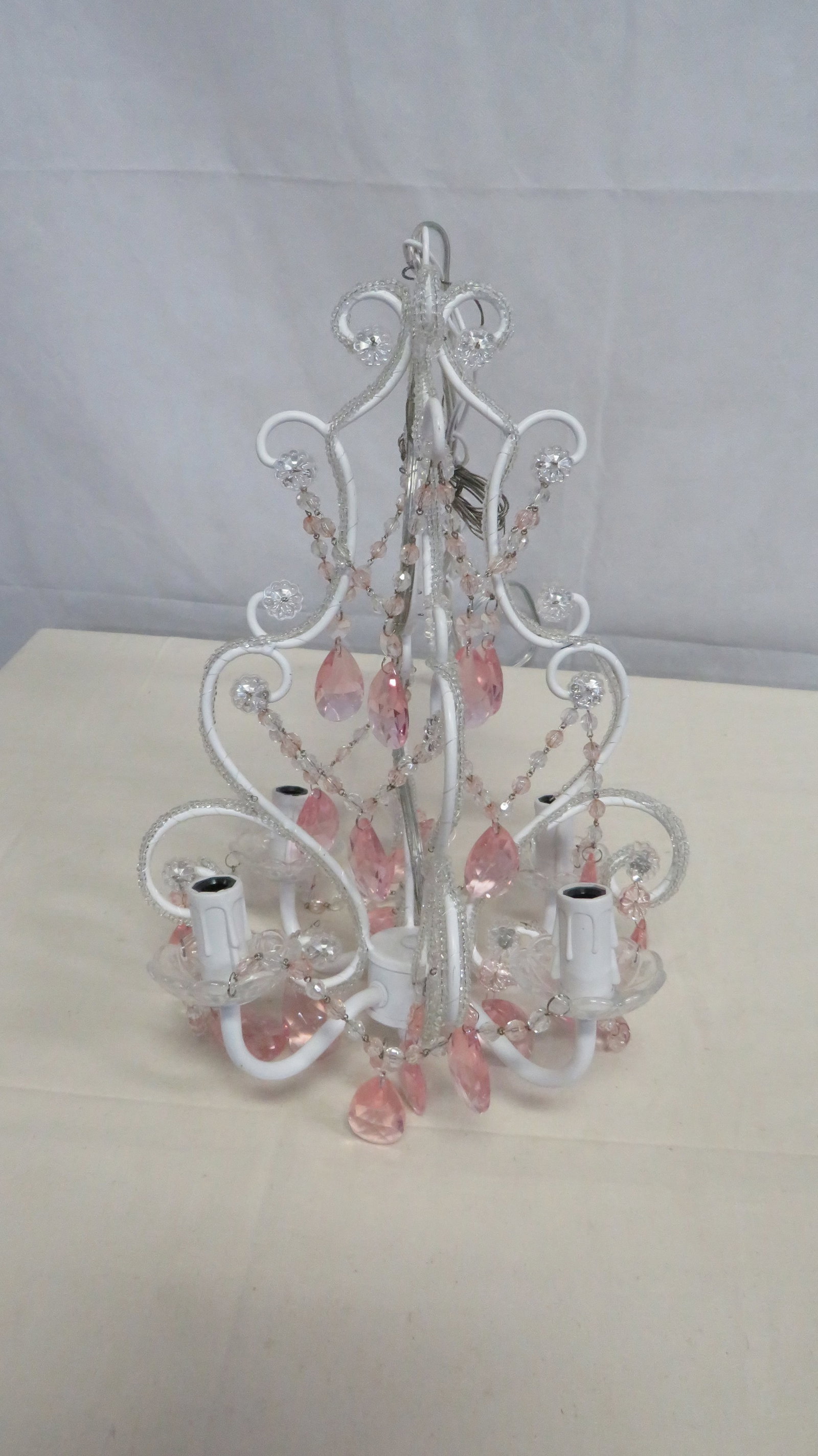 Pink Crystal 4-Light Swag Chandelier: Pink Crystal 4-Light Chandelier featuring a white scrolling metal frame with pink and clear faceted crystal prisms. includes long swag cord. 17"H x 12"D