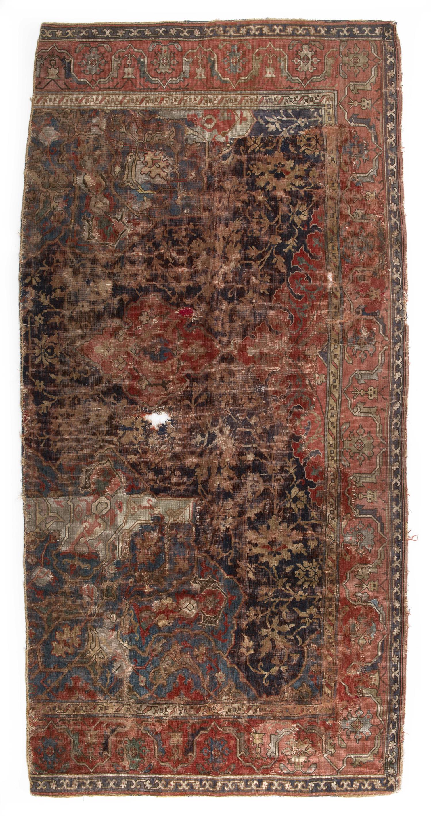 Partie de tapis Oushak antique en laine: Partie de tapis Oushak antique en laine à décor central floral bicolore et bordure principale à décor d'une frise de lotus styllisée sur champ rouge.220x107 cm