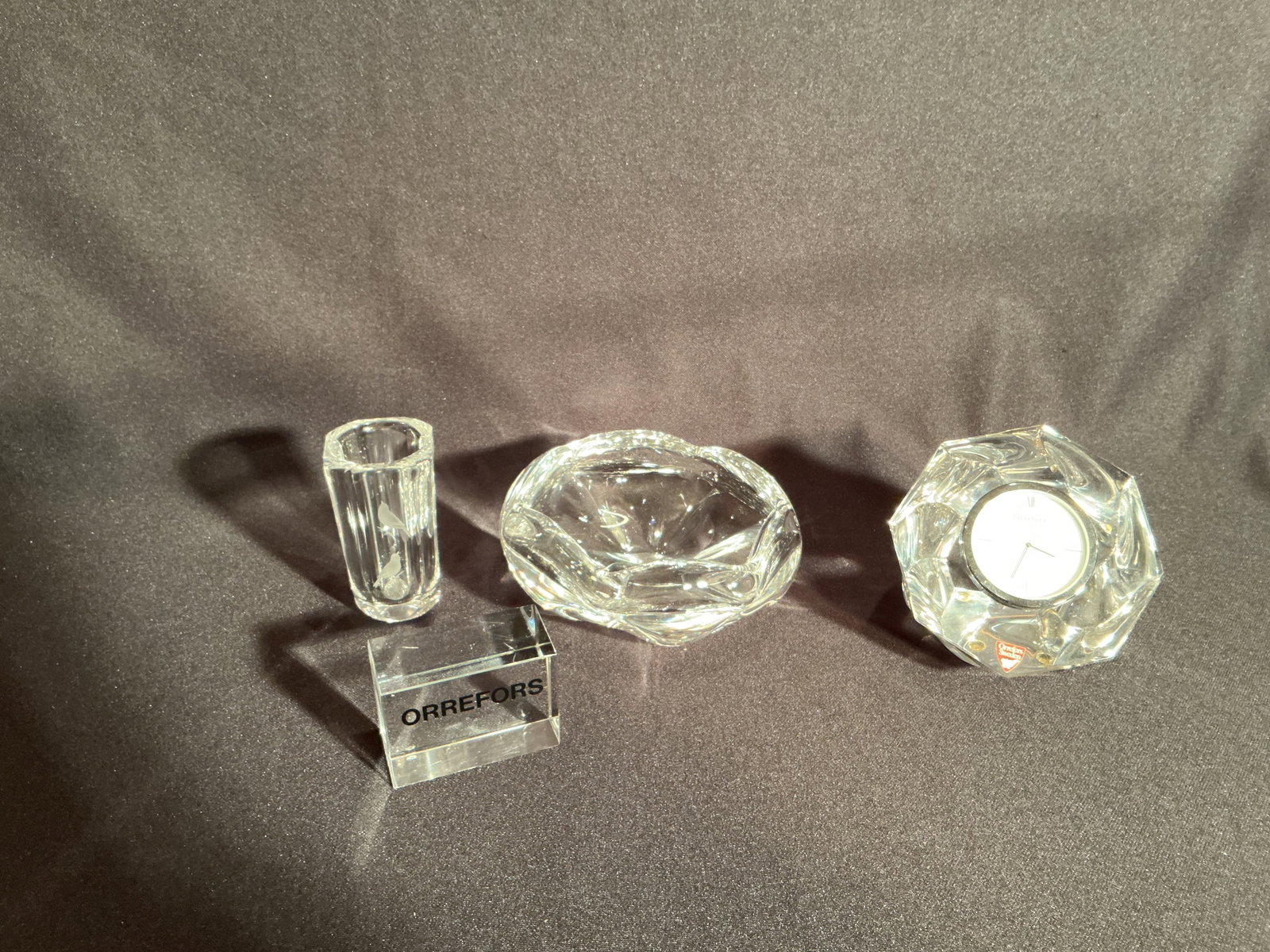 Four piece Orrefors Group: Bowl - 2" x 6", Vase - 3.75", Clock, Orrefors cabinet display sign.