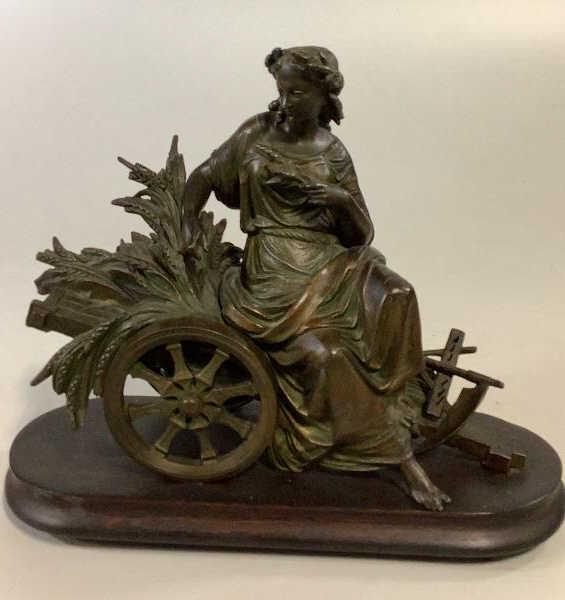 Bronze Figural Statue: In Grecian style, a woman resting on a grain cart, 12 x 14 inches, patinated bronze, mounted to a wooden plinth no signature