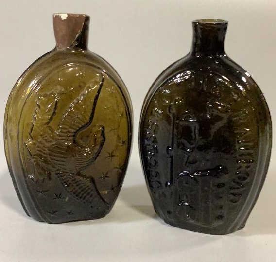 2 Amber Glass Flasks , Success to the Railroad: Hand blown, deep amber to brown glass flask - 1 with embossed American Eagle surrounded by Stars, and Success to the Railroad with horse pulling a wagon, 2 - both sides embossed with Success to Railro