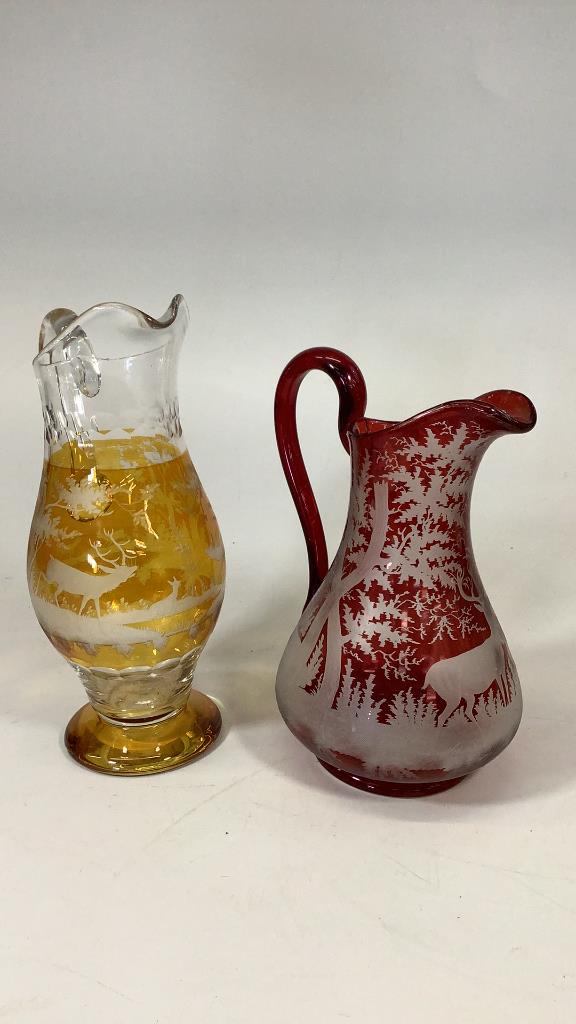 2 Bohemian Etched Glass Pitchers: Ruby Etched 10 inch pitcher with stag and Forest scene, applied handle, 12 inch amber etched pitcher, stag and woodland thumb print collar and lower body