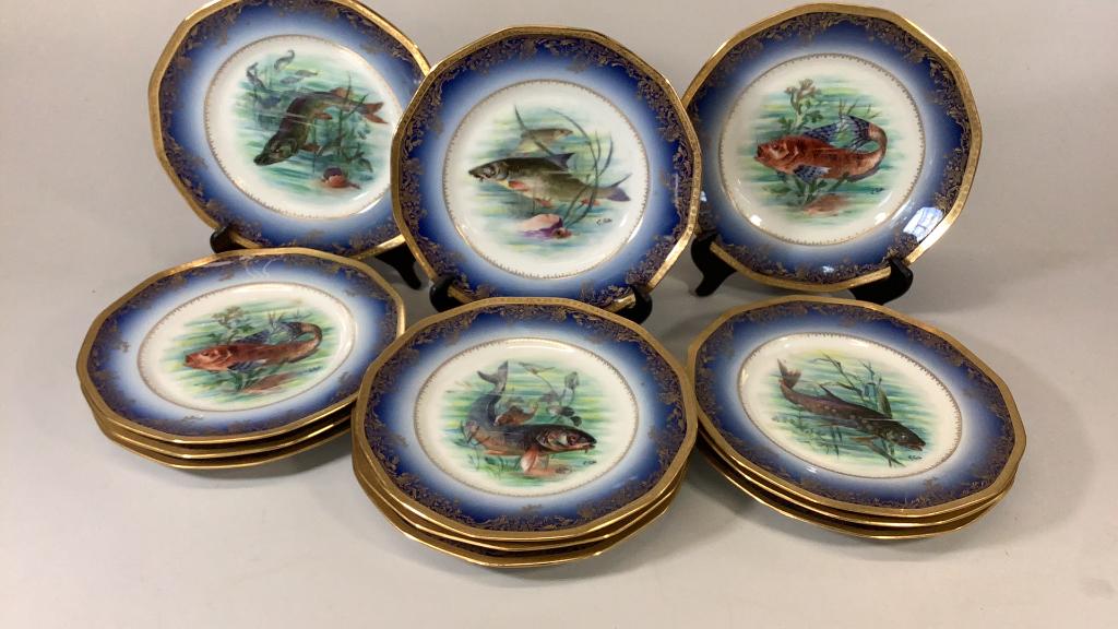 Limoge Porcelain Fish Plates: Set of 12 Artist signed Limoge French Porcelain Plates, signed L.Lubis with shaded blue banding and gilt florals on a scolloped rim, each 9.5 inches, stamped Limoge, also green triangle stamp for Godi
