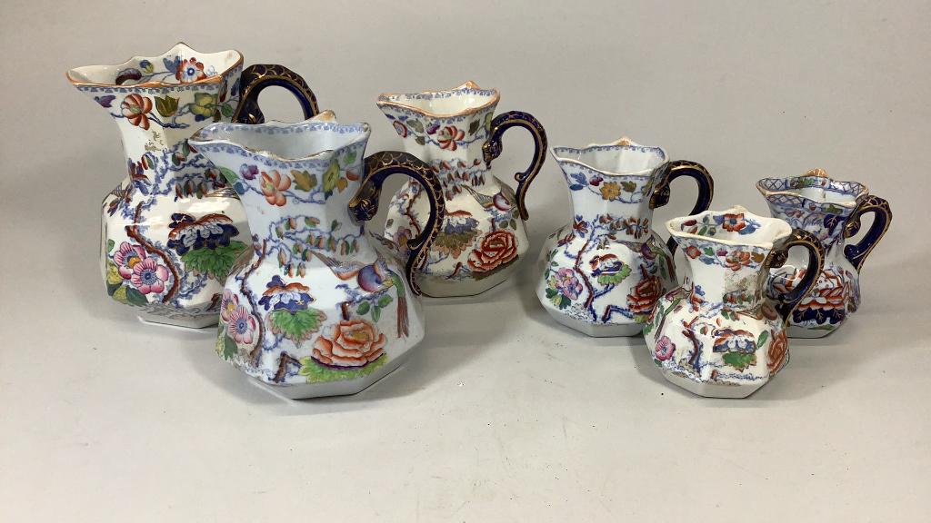 Assembled Set of 6 Masons Gaudy Ironstone Pitchers: 6 graduated size pitchers, all with serpent handles in cobalt, peacocks, florals, budding trees on ivory ground, light wear stains as appropriate for age