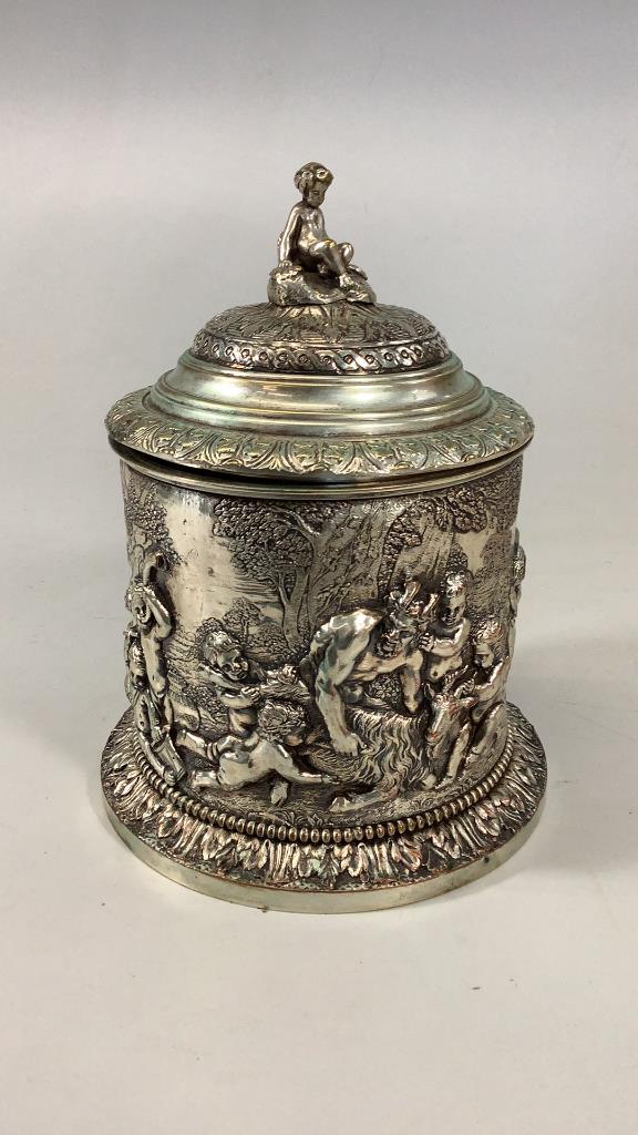 Lidded Silverplate Biscuit Barrel: 9 x 6 inch hinged container with relief designs depicting Pan and other Greek mythological creatures in a woodland scene, heavily embossed with foliate rim and base, seated Puti finial, possibly silve