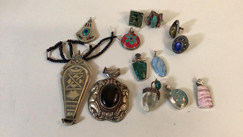 Unmarked Jewelry: 3 inch pendant with relief animals on black center stone, 4 inch pendant, chased design, beaded 7 varied stone pendants, 4 rings, none marked, stones not tested