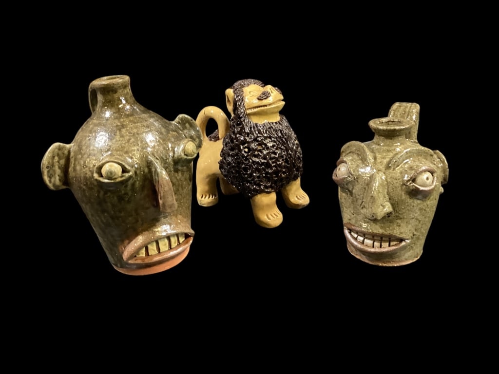 Three Stoneware Objects: Crystal King signature Lion, 5 x 7 inches, standing with head up, lots of curly mane.. ( tail cracked when firing), 5 inch tall miniature face jug by Michel Bayne green glossy glaze, double row teeth,