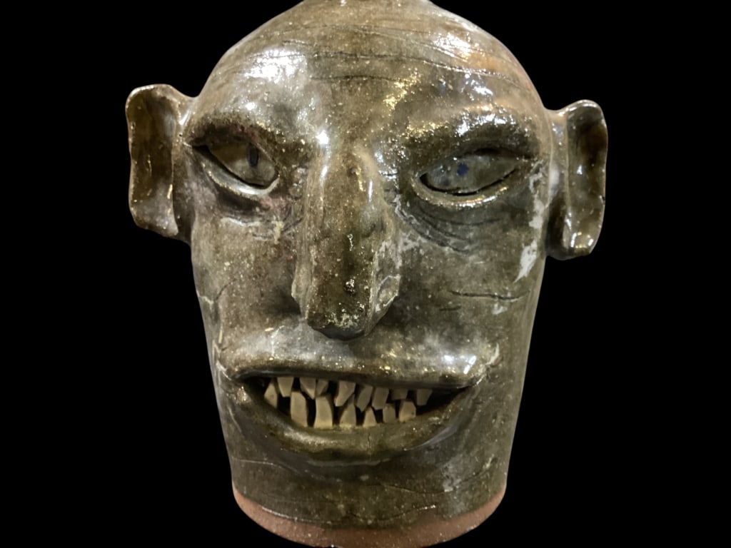 Joe Reinhardt Face Jug: Ugly Face Jug, big mouth with large teeth, flat eyes, big ears and nose. Some wrinkle lines to forehead. Stamped at base