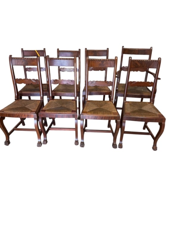 Set of Eight Figured Mahogany Chairs: Early 20th C, Set of eight chairs crafted from figured mahogany with rush seats and paw feet. 5 side and 1 armchair, , featuring carved backrests with decorative detailing. Unique feet design suggests