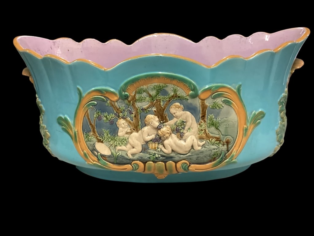 Minton Majolica Jardinere: Rococo Jardinere, turquoise glazed lobed body, oval form of 23 inches, with fine relief panels depicting Puti in rose garden. C scroll borders, glazed pink interior. Impressed marks to base as Minton,