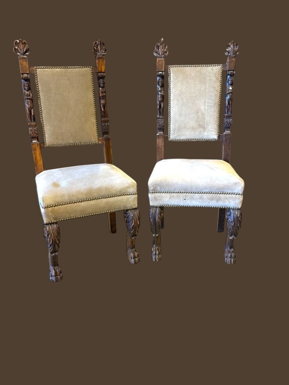 Pair of Carved Walnut Renaissance Revival Chairs: Pair of late 19th-century carved walnut hall chairs featuring figural stiles with cherub masks, acanthus finials, and deeply carved paw feet. Upholstered in soft taupe velvet with brass nailhead trim.