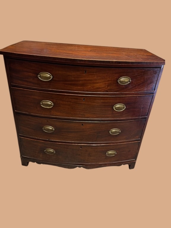 Federal Mahogany Bowfront Chest of Drawers: Early 19th-century mid atlantis mahogany bowfront chest featuring four graduated drawers with dovetail joinery and oval brass pulls. Beautifully figured mahogany top with contrasting flame inlay and s