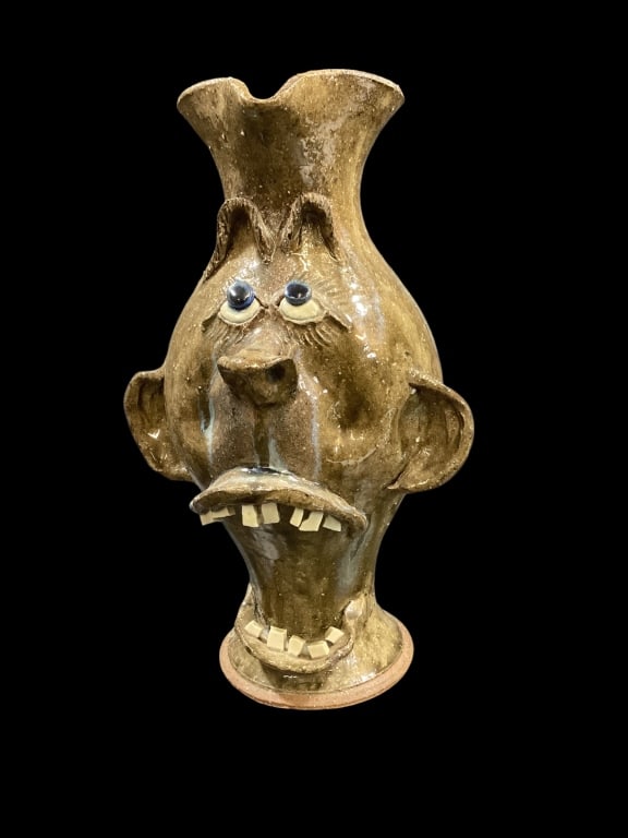 Southern Folk Pottery Face Jug: Caricature Face Jug, featuring over done wide mouth with double rows of teeth, pronounced nose, big ears, arched eyebrows and cobalt stone eyes, 13.5 inches tall, applied shaped handle. Alkaline glaze