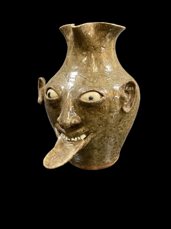 Southern Folk Pottery Face Pitcher: Don Craig Ugly Face Pitcher, hand sculpted 12 inch pitcher with buggy blue eyes, single row China teeth, oversized tongue. Wavy lines to shoulder. Rich alkaline glaze. Signed and dated 1998