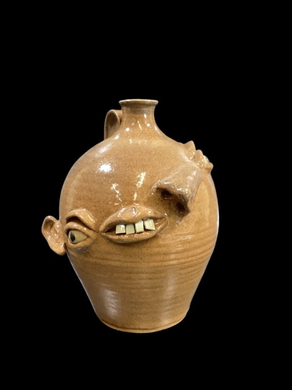 Don Craig Crazy Face Jug: Souther Folk Pottery face jug, alkaline glazed with comical misplaced facial features. Off set mouth with China teeth, pronounced nose, and misshapen ears. , buggy blue eyes. 11 inches tall signed in