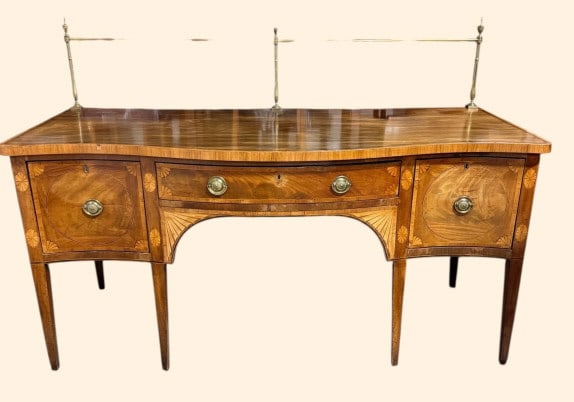 George III Inlaid Mahogany Sideboard: A refined early 19th-century George III mahogany sideboard, finely inlaid with satinwood banding and oval fan paterae throughout. The gently serpentine top is fitted with a removable brass gallery and