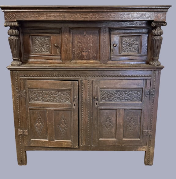 18th C English Revival Carved Oak Court Cupboard: Early British Oak Court cupboard, carved panels and columns, inlaid cornice and door. Very unusual pull up middle door exposes bank of hidden drawers, minor losses consistent with age, needs minor res