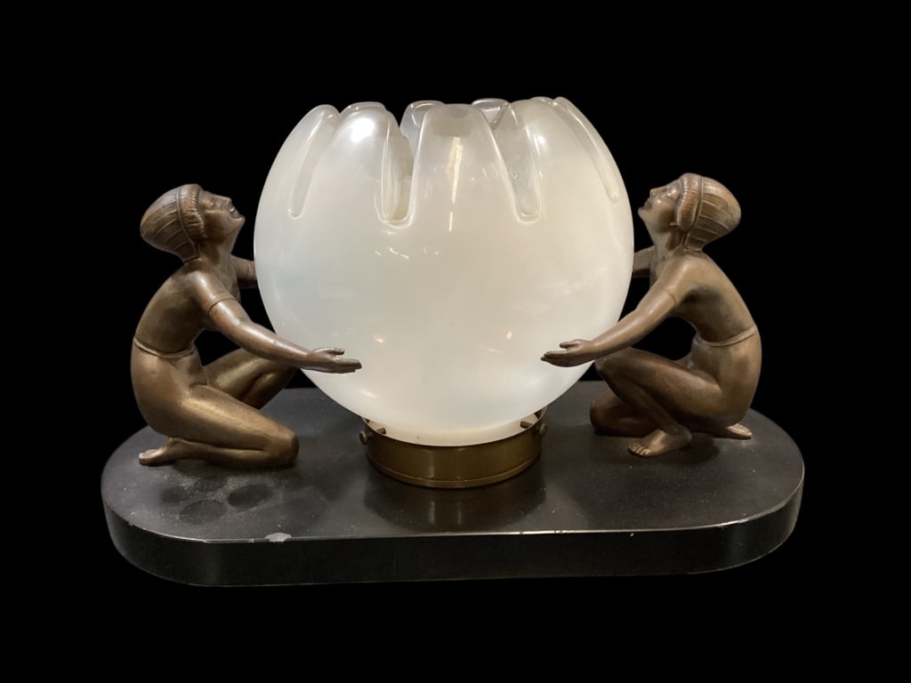 Art Nouveau Figural Table Lamp: Pair of Egyptian style kneeling figures supporting a frosted glass orb shade. 15 inches long, it is mounted a black base. The figures in bronzed finish metal. Crafted in style of Frankart, but