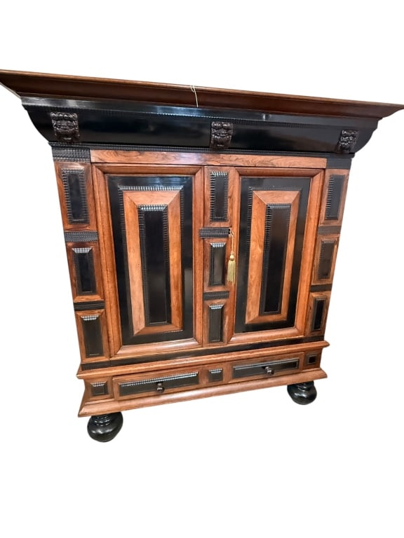 Antique Dutch Kas Armoire: Oak, architectural design features a heavy overhanging cornice supported by mythological lion-mask corbel brackets and a striking ebonized frieze. The facade showcases raised geometric panels