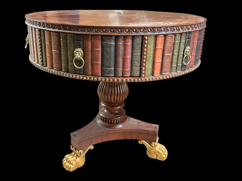 Embossed Leather Library Book Table: Unmarked but likely by Maitland Smith, trompe l'oeil books surround leather topped table, one actual working drawer, pedestal base with 3 gold paw feet..surface scratches to table, top leather with