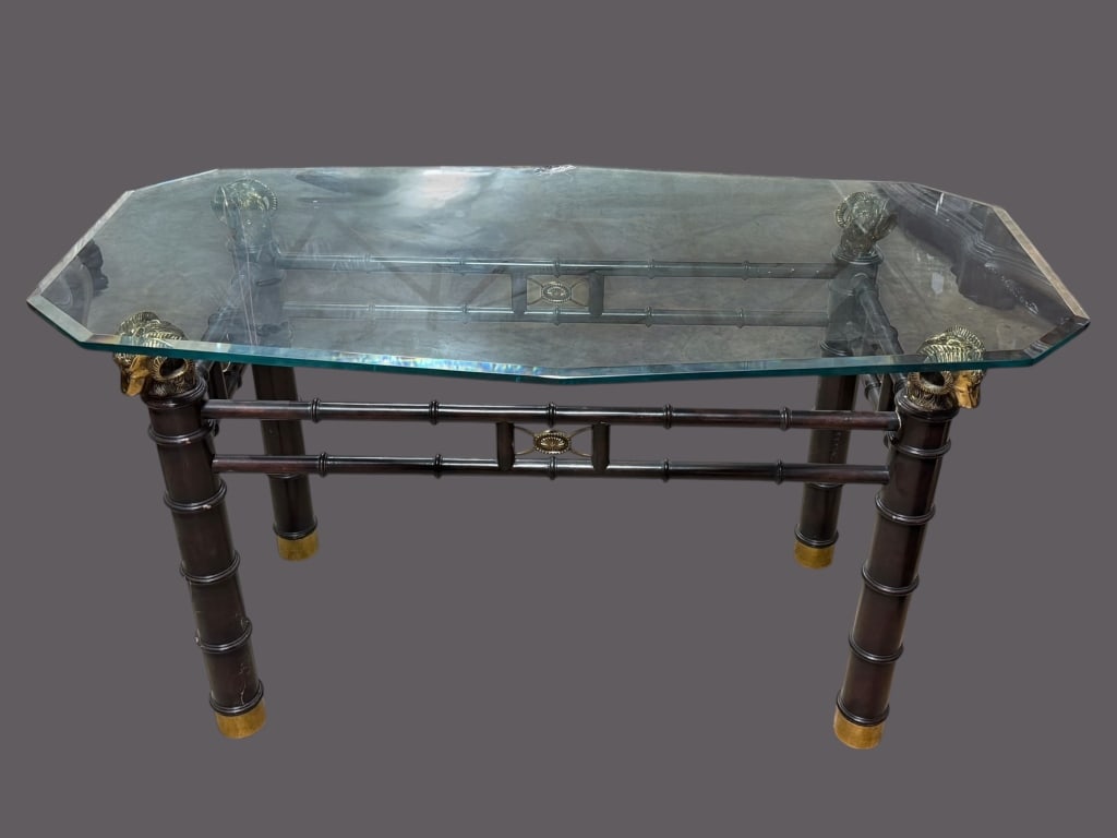 Brass Rams Head Console Table: Faux wood finish frame topped with 4 large rams heads, brass capped feet, shaped glass top with beveled edge, Made in the Philippines by Lineage Furniture for Maitland-Smith..finish loss to faux wood