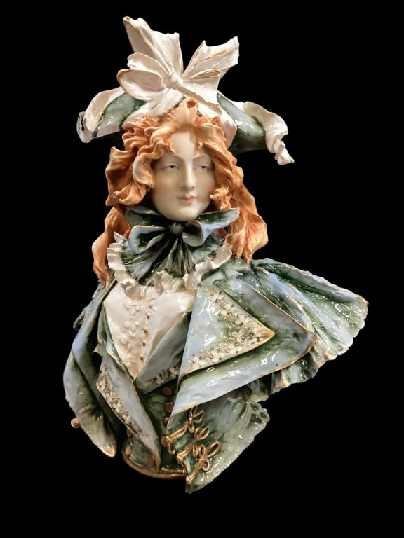 Art Nouveau Porcelain Bust: Crafted in Turn Teplitz, this large bust shows a woman with red hair, Elaborate dress with large ruffled bow and wide brim hat. Naturalistic form in typical Art Nouveau style. 20 inches tall, stamped
