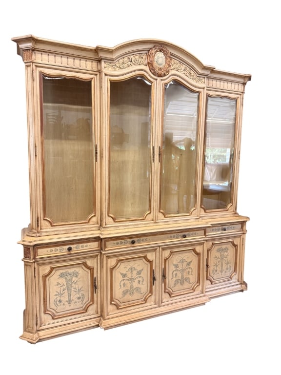 Provincial Style Hand-Painted Breakfront: A grand Provincial style breakfront china cabinet featuring a two-piece construction with an antiqued cream-and-gold finish. The upper section boasts a central arched crest rail adorned with scrolled