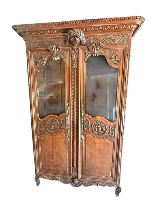 French Louis XV Style Carved Oak Armoire: Early French Louis XV style oak armoire displaying a wealth of ornate, hand-carved details and a rich prominent wood grain finish. The upper architecture features a heavily molded, egg-and-dart