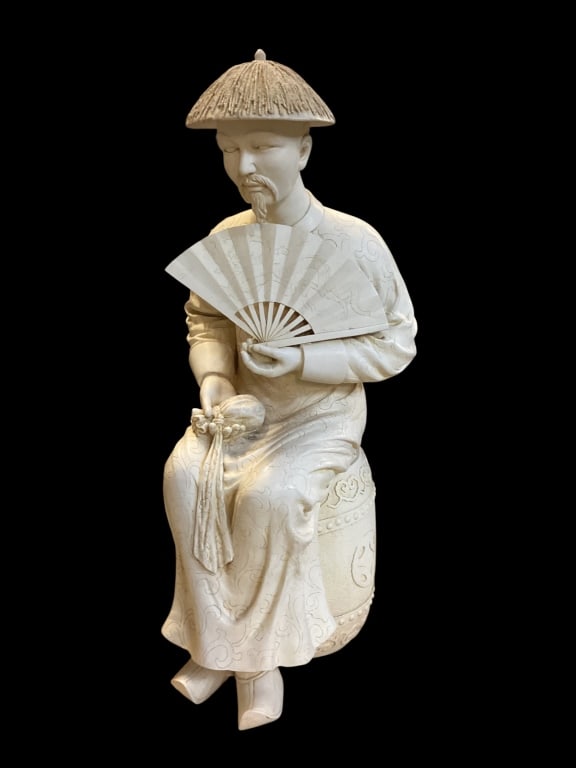 Ceramic Sculpture of Asian Man: Decorative Export figure of a seated Asian scholar, holding a fan, and a money bag, Traditionally dressed,