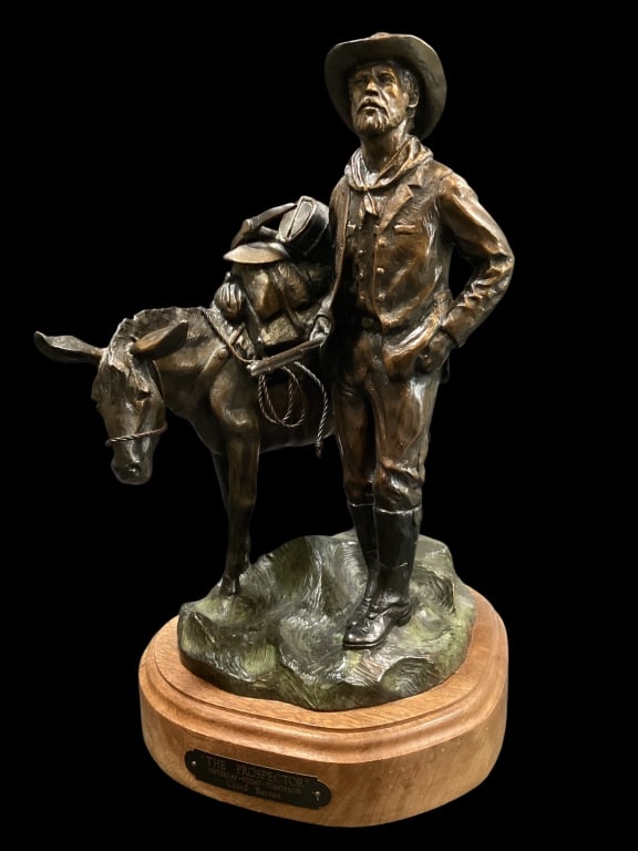 Western Theme Sculpture: Cast bronze sculpture titled The Prospector creat by Artist Cloyd Barnes, 1998. Features a tool laden pack mule with a bearded prospector. 13 inches tall, mounted to a wooden swivel base.