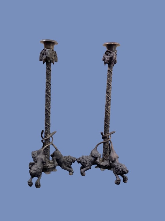 Pair Bronze Figural Candlesticks: Neoclassical styled Figural candlesticks, 14 inches tall. Designed with rams heads at cup, with crouching lions at the tripod base. A climbing vine motif with beaded candle cups, petal form base