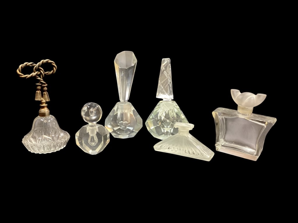 Collection of Crystal Perfume Bottles: Six clear Crystal perfume bottles, including a facet cut Art Deco style with geometric prism stopper. Heavy hand cut diamond facet bottle with shaped stopper, Oscar de la Renta bottle with frosted gla